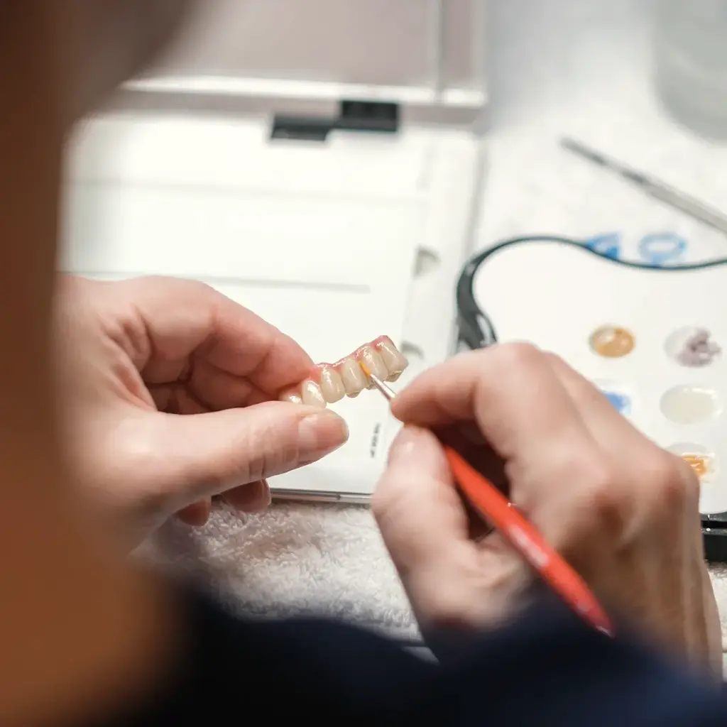 Feinarbeit mit dem Pinsel an einer Keramikkrone
